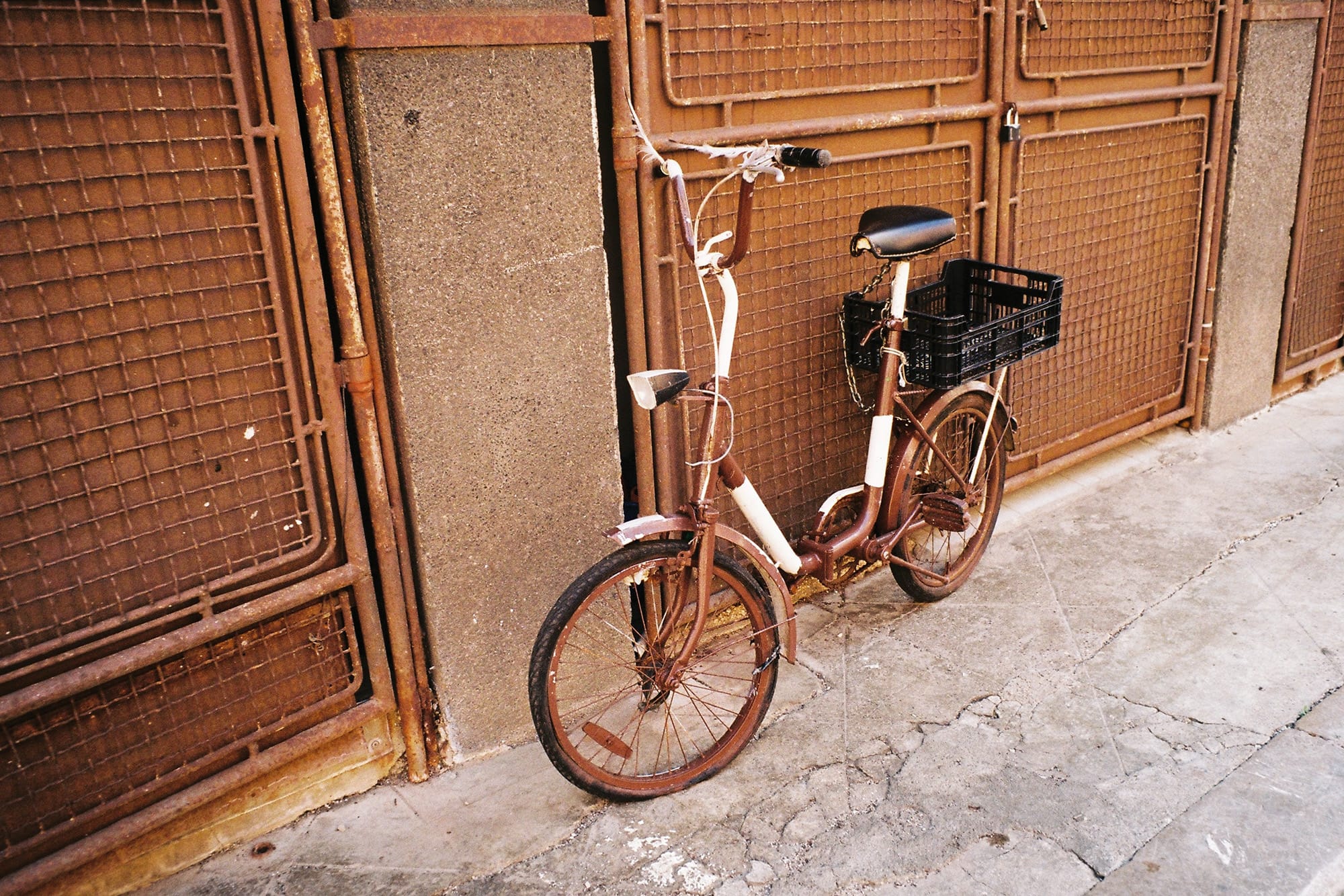 A rustic bicycle leaning against a weathered, rusty metal wall.