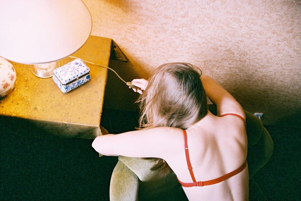 Young woman in lingerie sitting on a green chair, playing with a lamp.