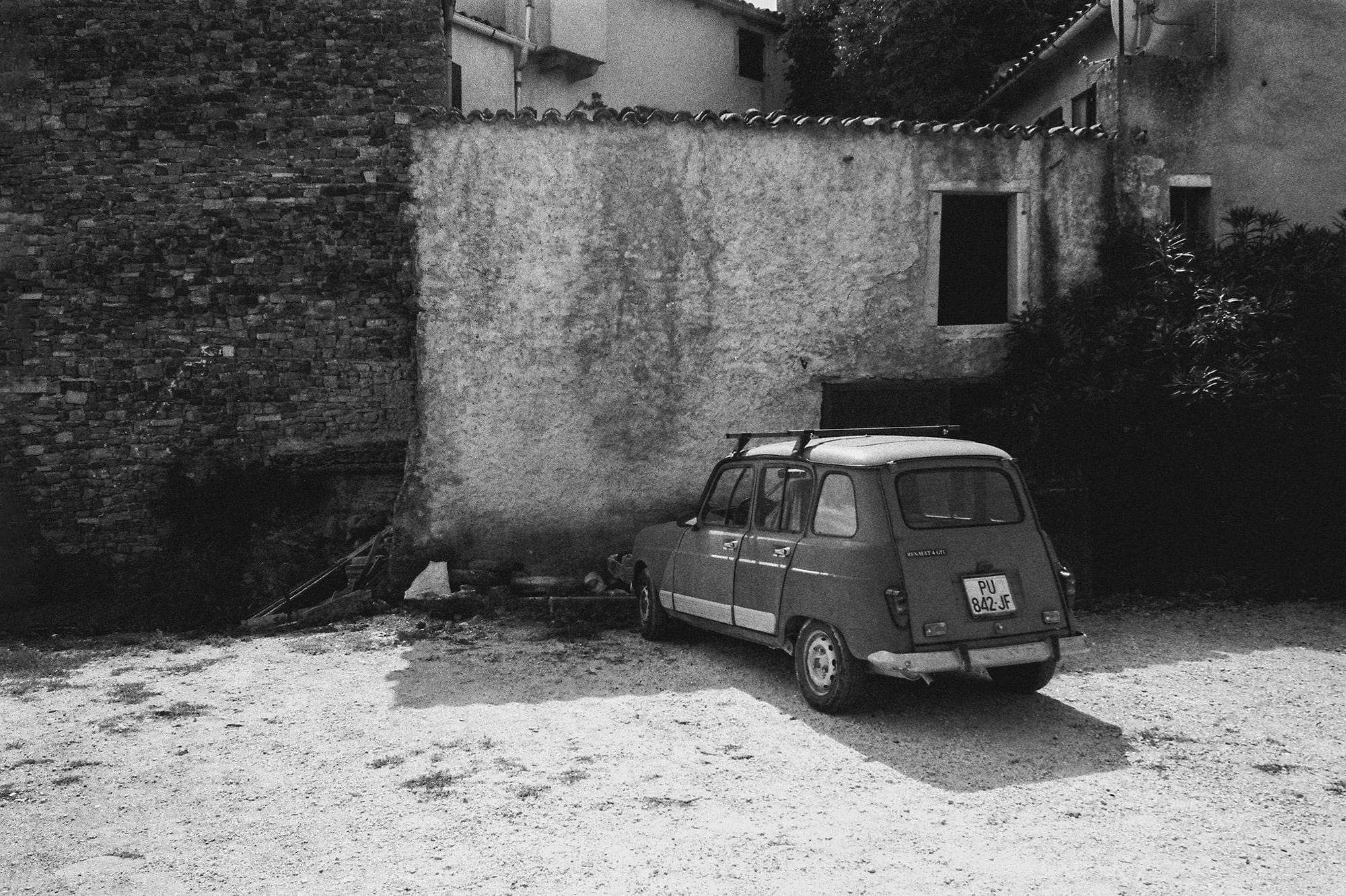 A vintage Renault parked in front of a rustic, stone house in rural Croatia.