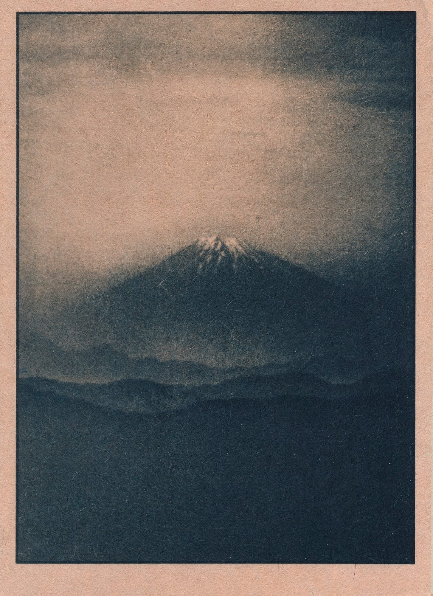 A cyanotype photograph of a distant, snow-capped mountain rising above a dark, misty landscape.