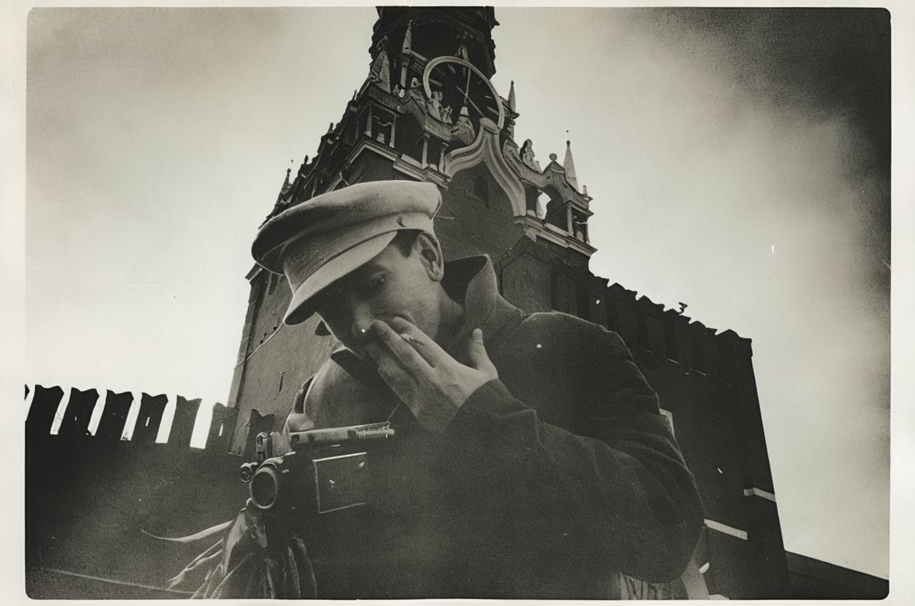 Retro photo of a photographer holding a cigarette and camera, in front of a clock tower.