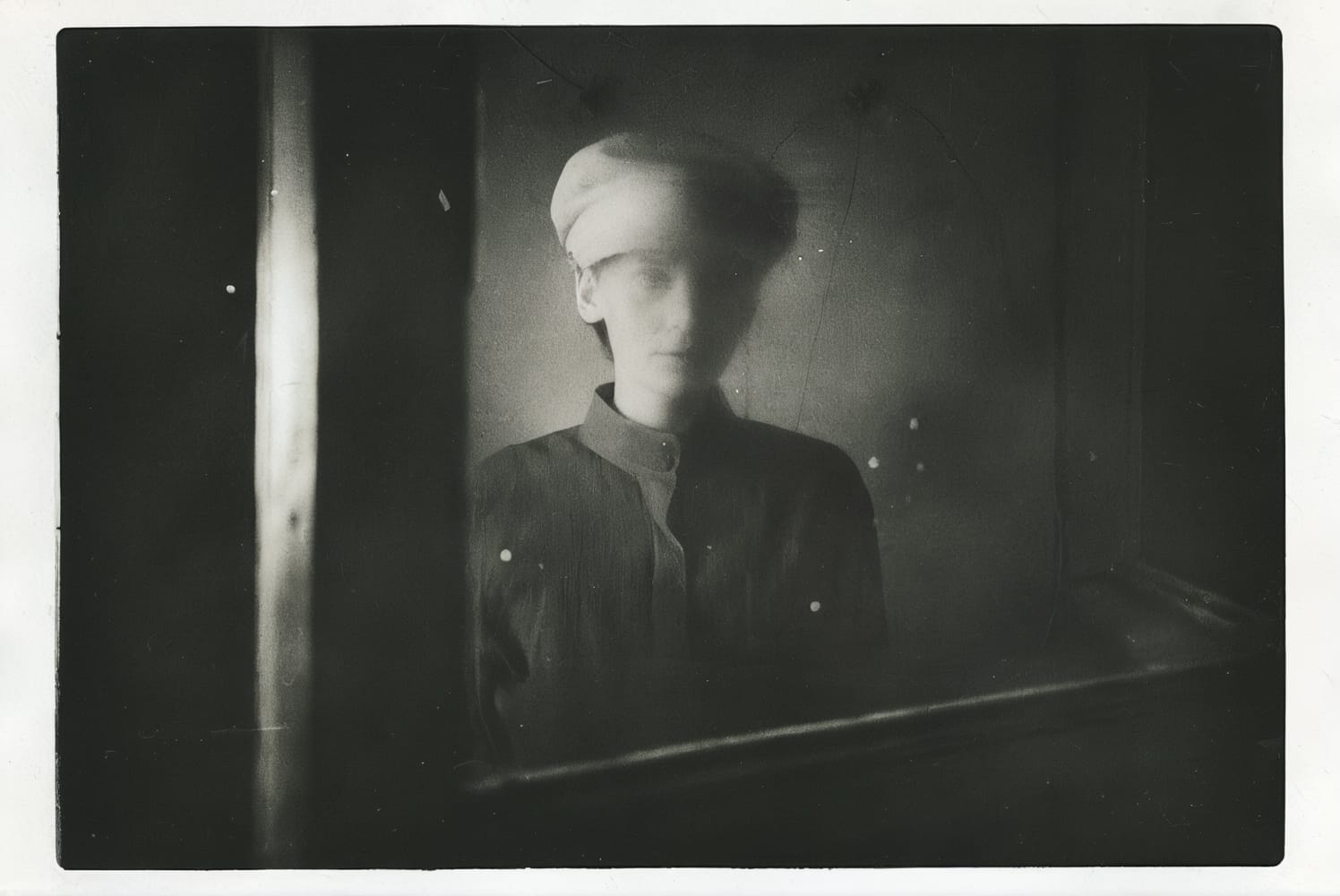 Vintage-style portrait of a woman in a hat and dark clothing.