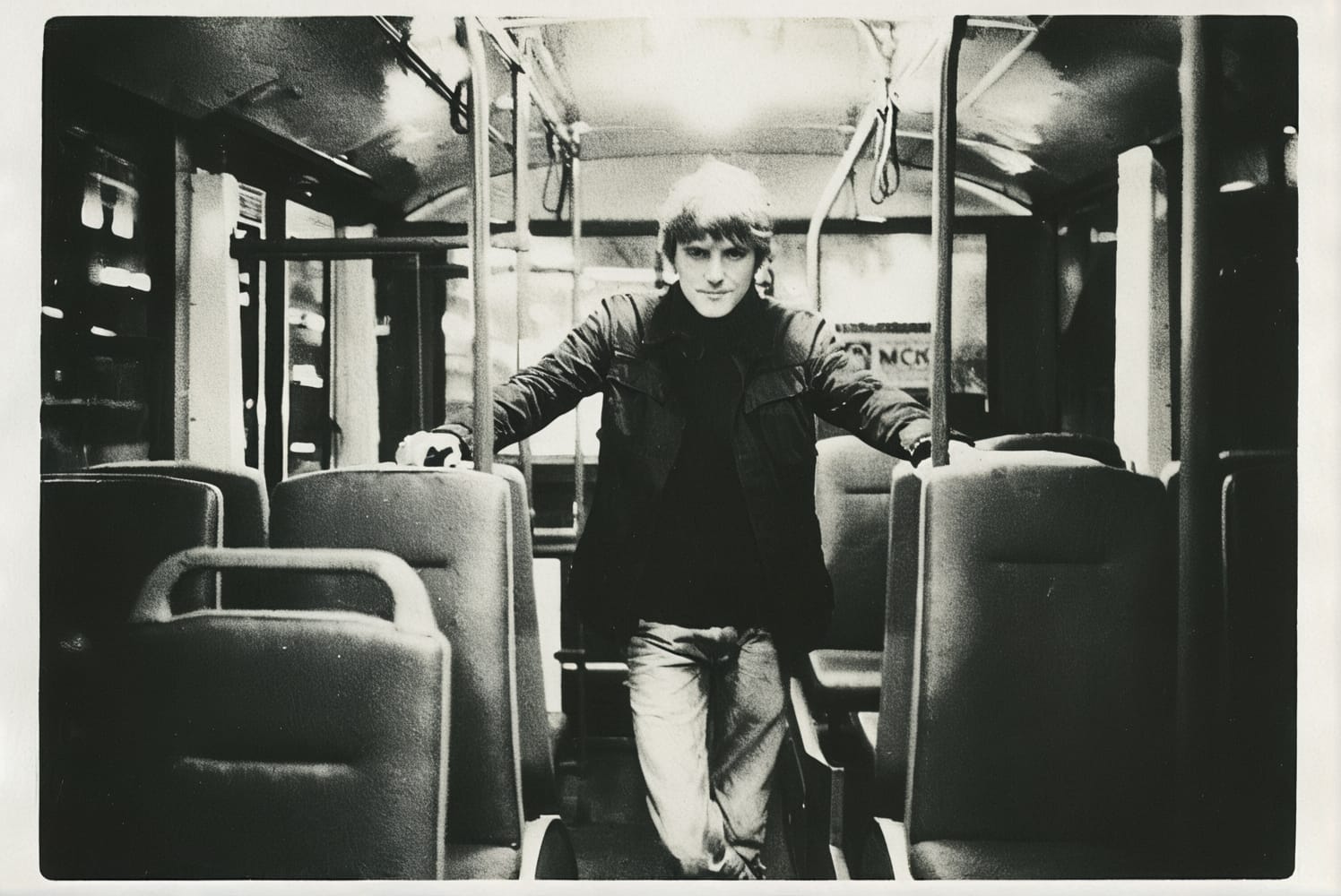 Monochrome photo of a man standing nonchalantly on a bus.