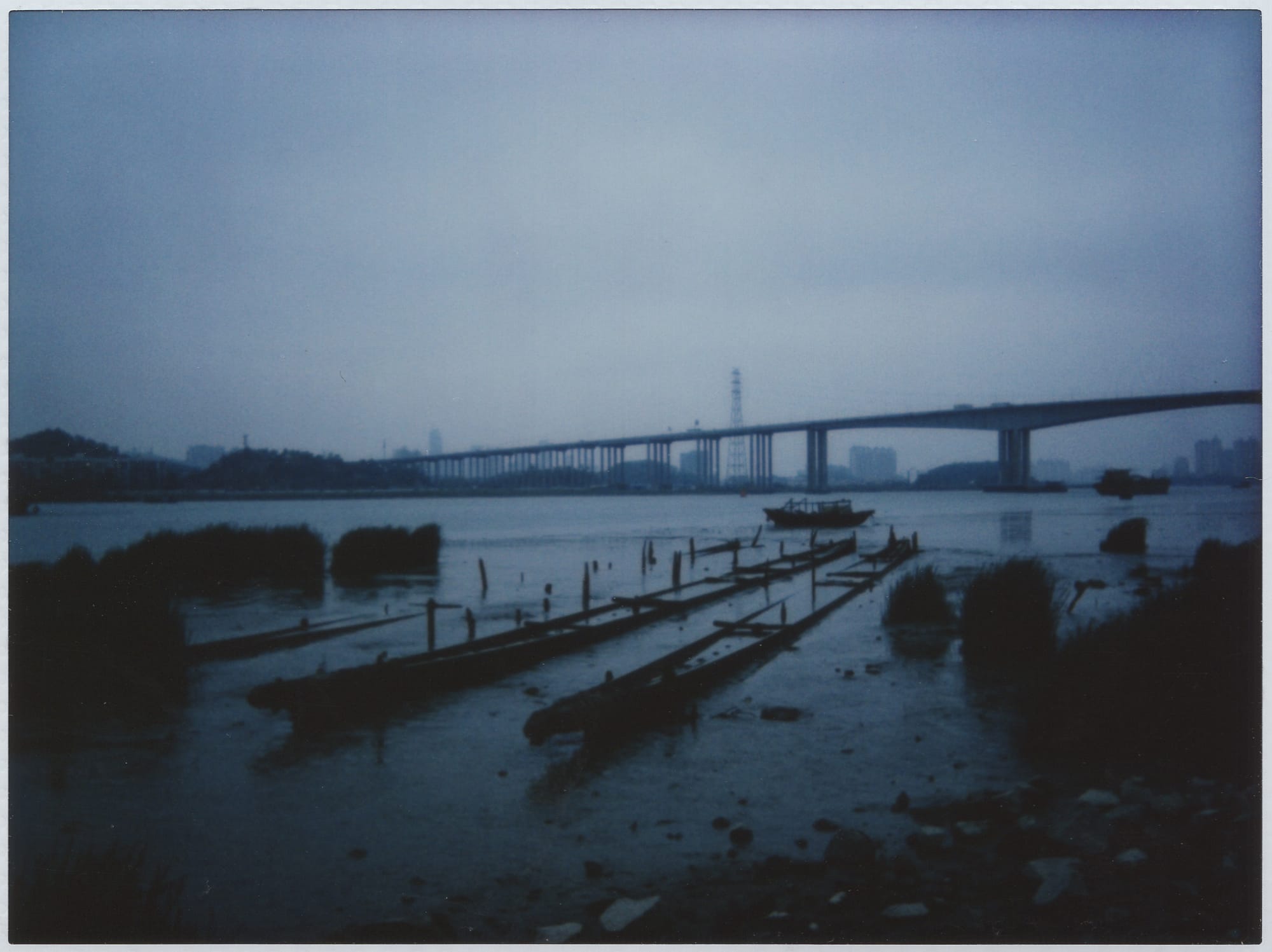 A waterfront scene with a bridge in the distance, shot with a Leica Sofort on Fujifilm Instax film.