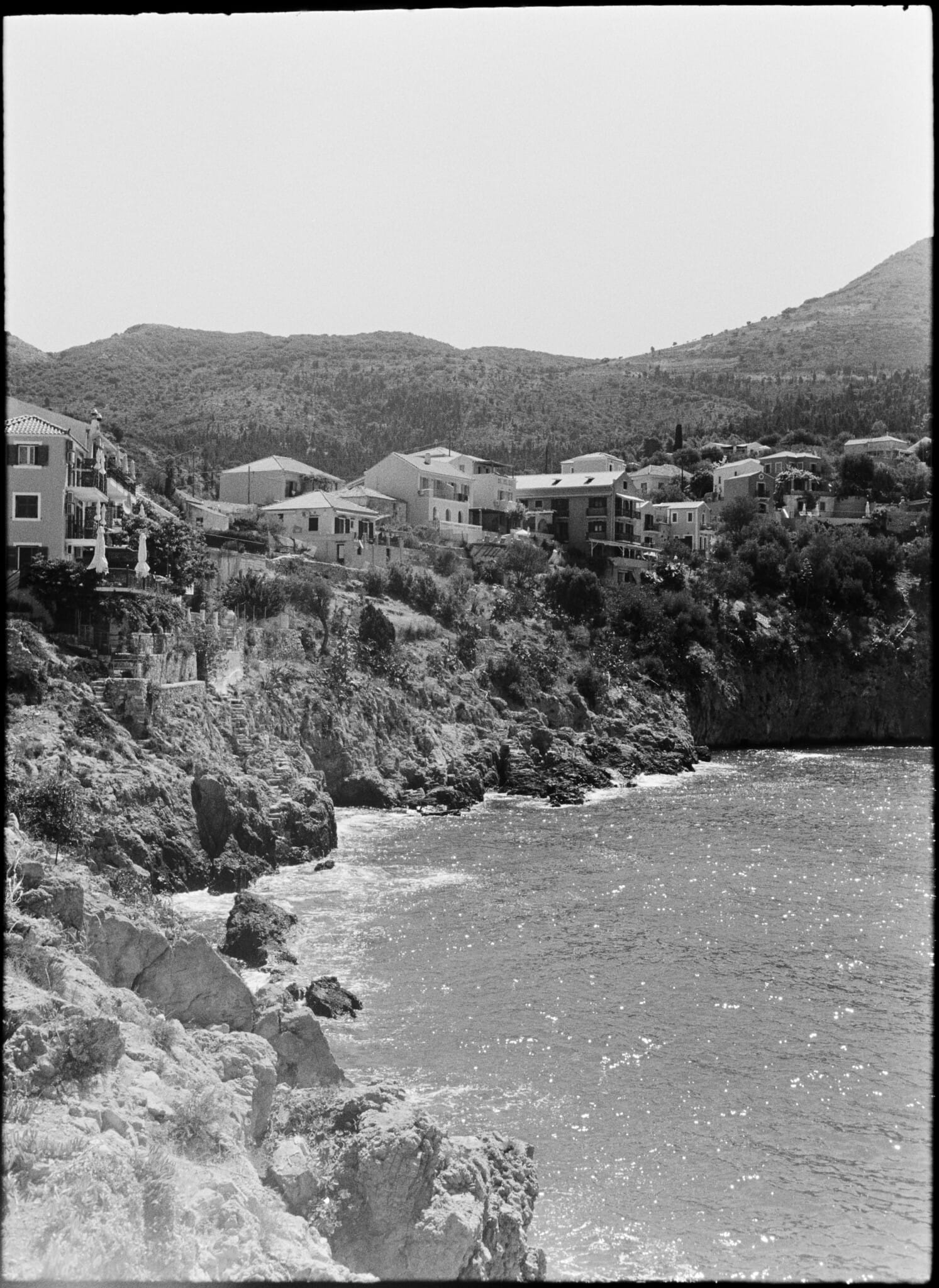 Black and white photo of a coastal village nestled on a rocky hillside.