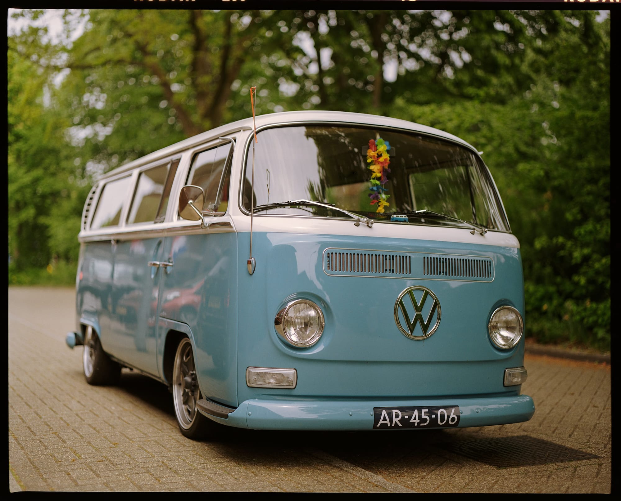 Classic light blue Volkswagen camper van parked on a paved road.