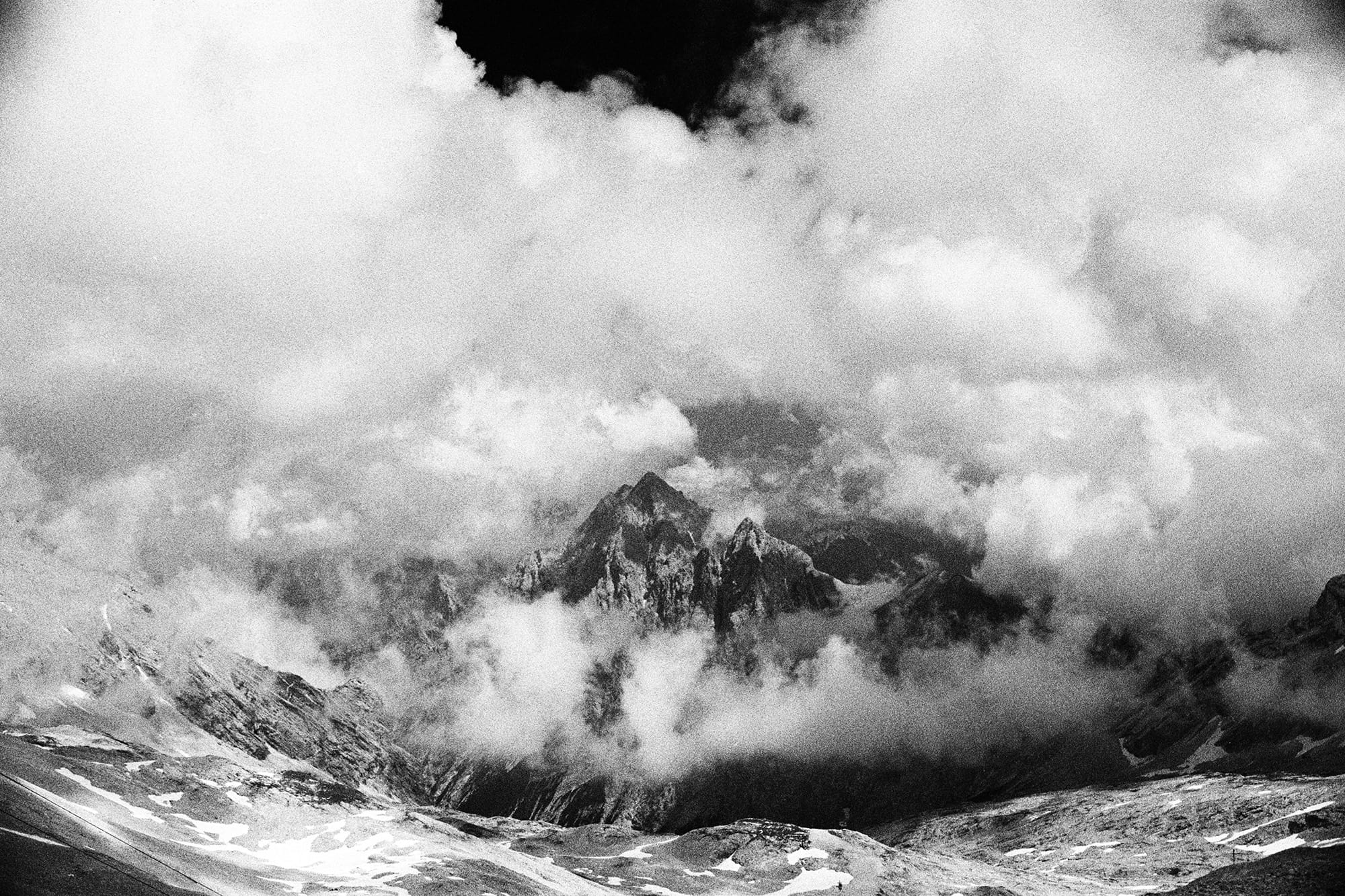 Striking black and white photo of mountain peaks shrouded in mist and clouds.