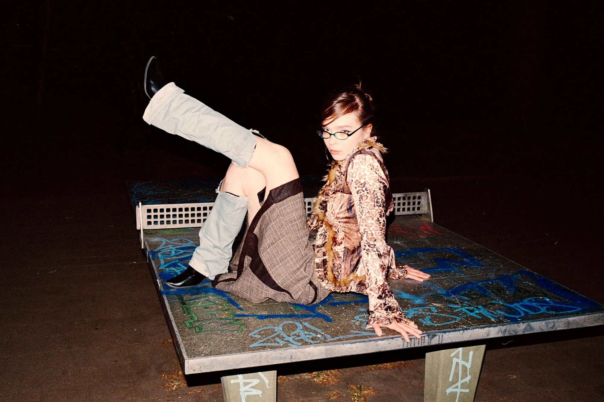 Young woman in a leopard print blouse strikes a pose on a ping pong table.