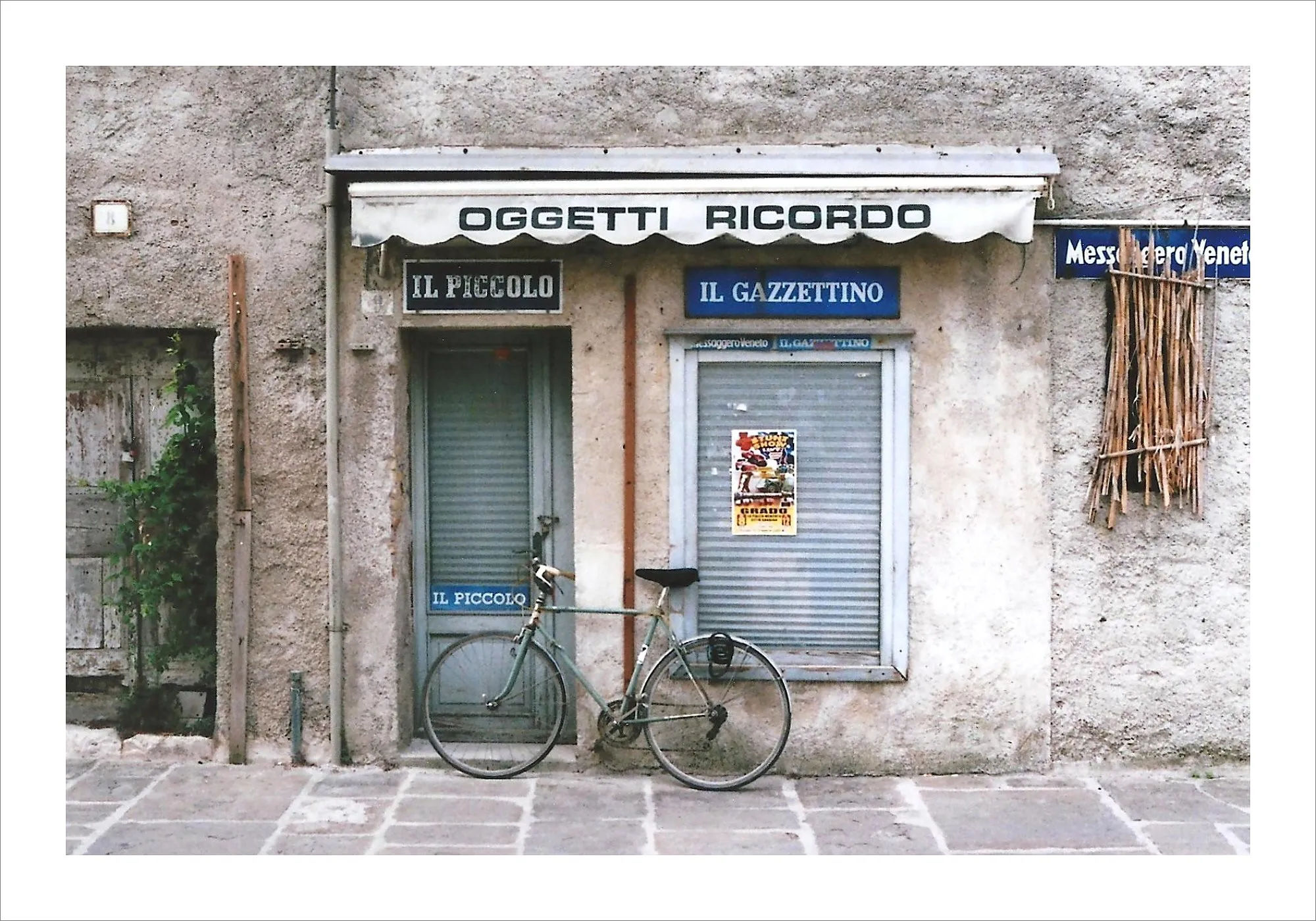 Italian newsstand storefront with bicycle leaning against shutters.