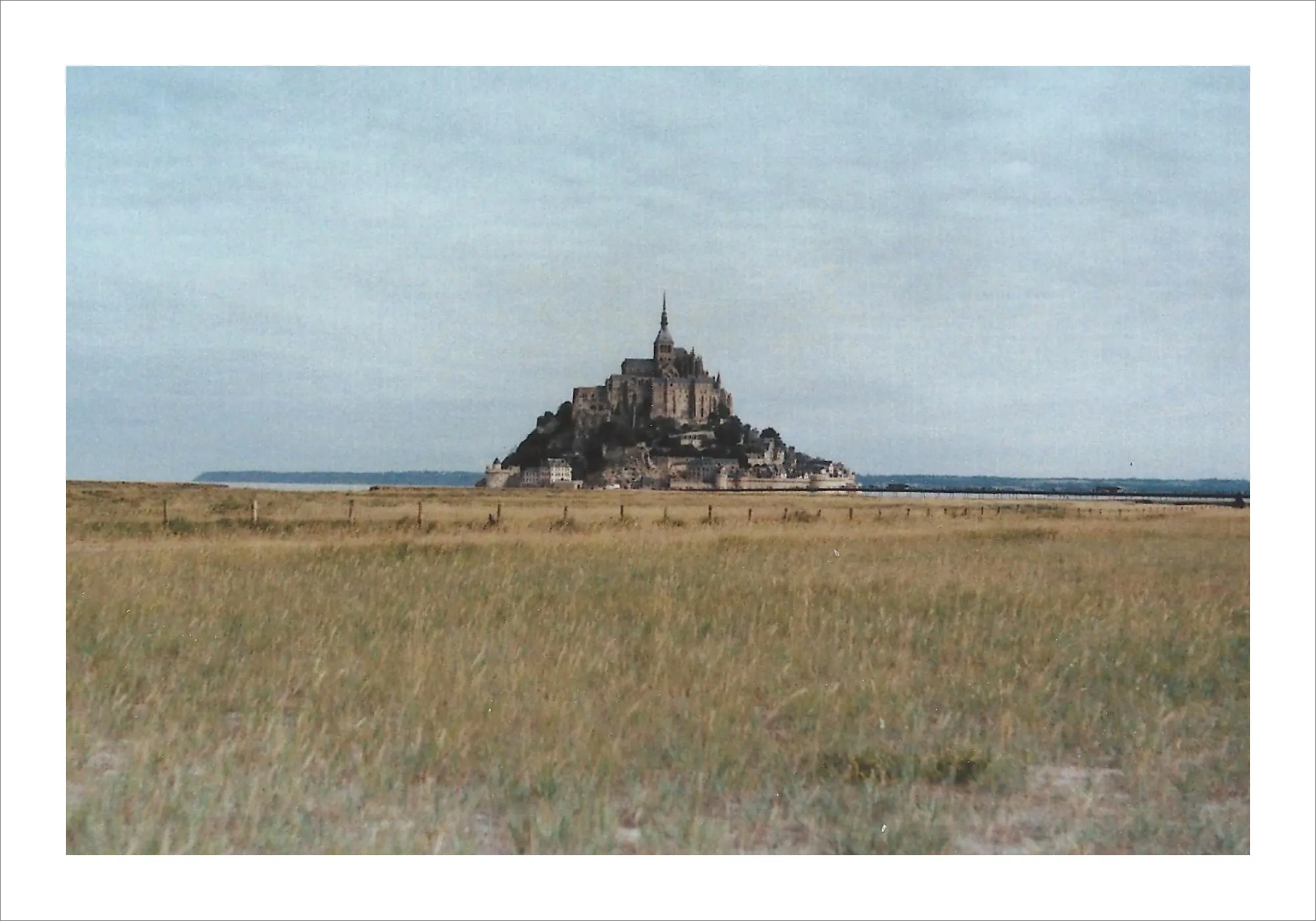 Mont-Saint-Michel abbey across fields in Normandy, France on film.