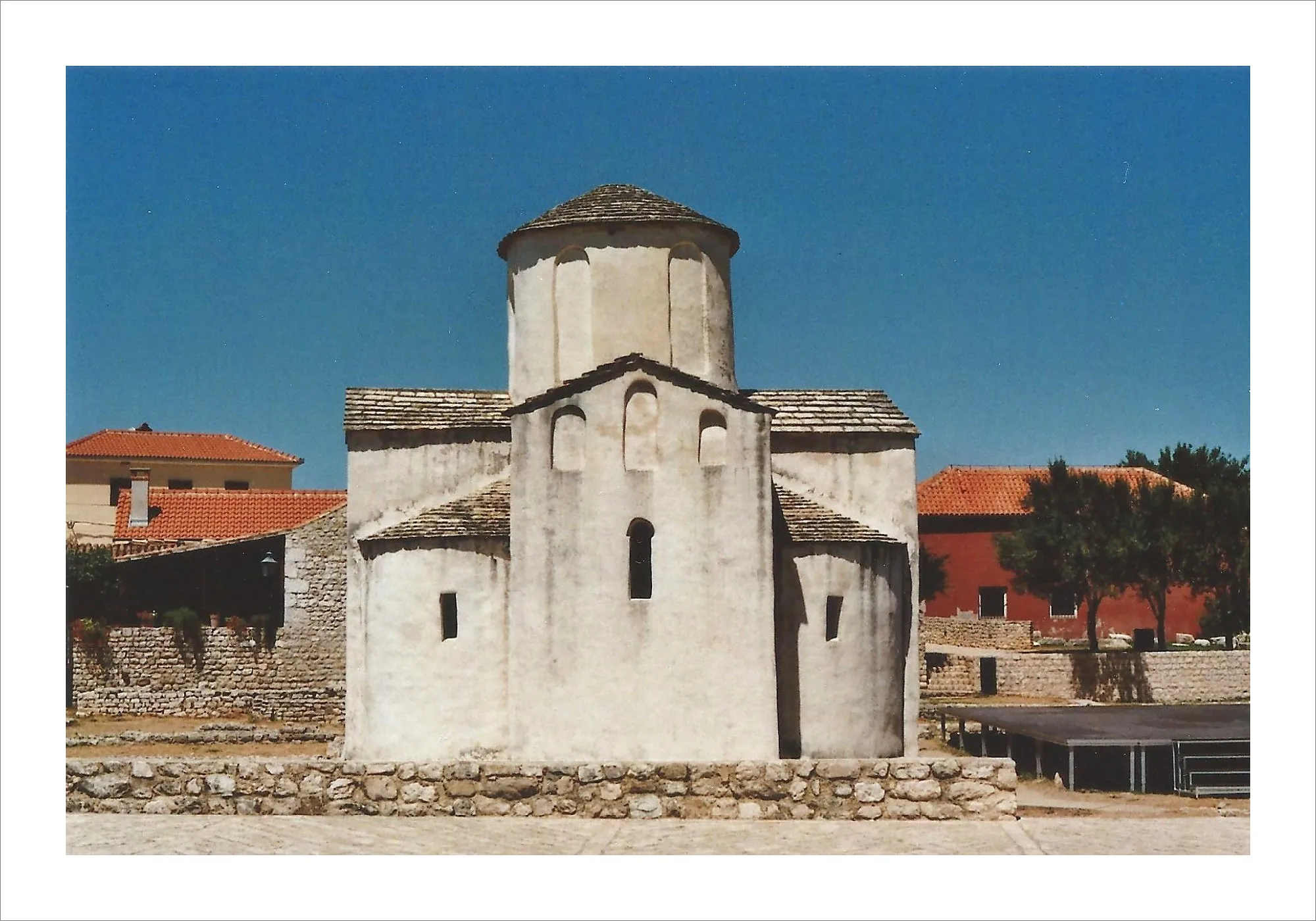 Small white stone church with round dome in Croatian town.