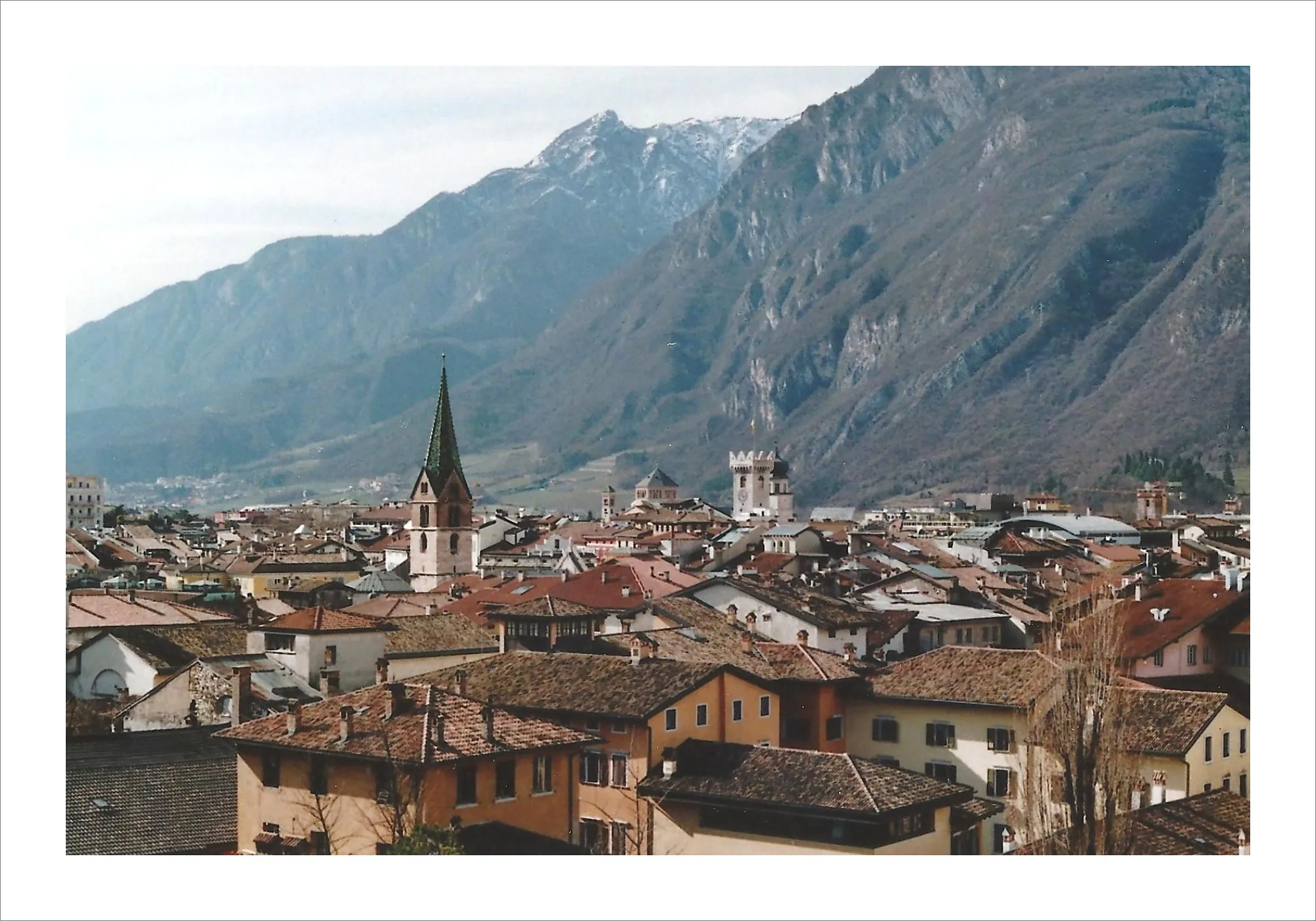 Alpine town rooftops with mountains in background on film.