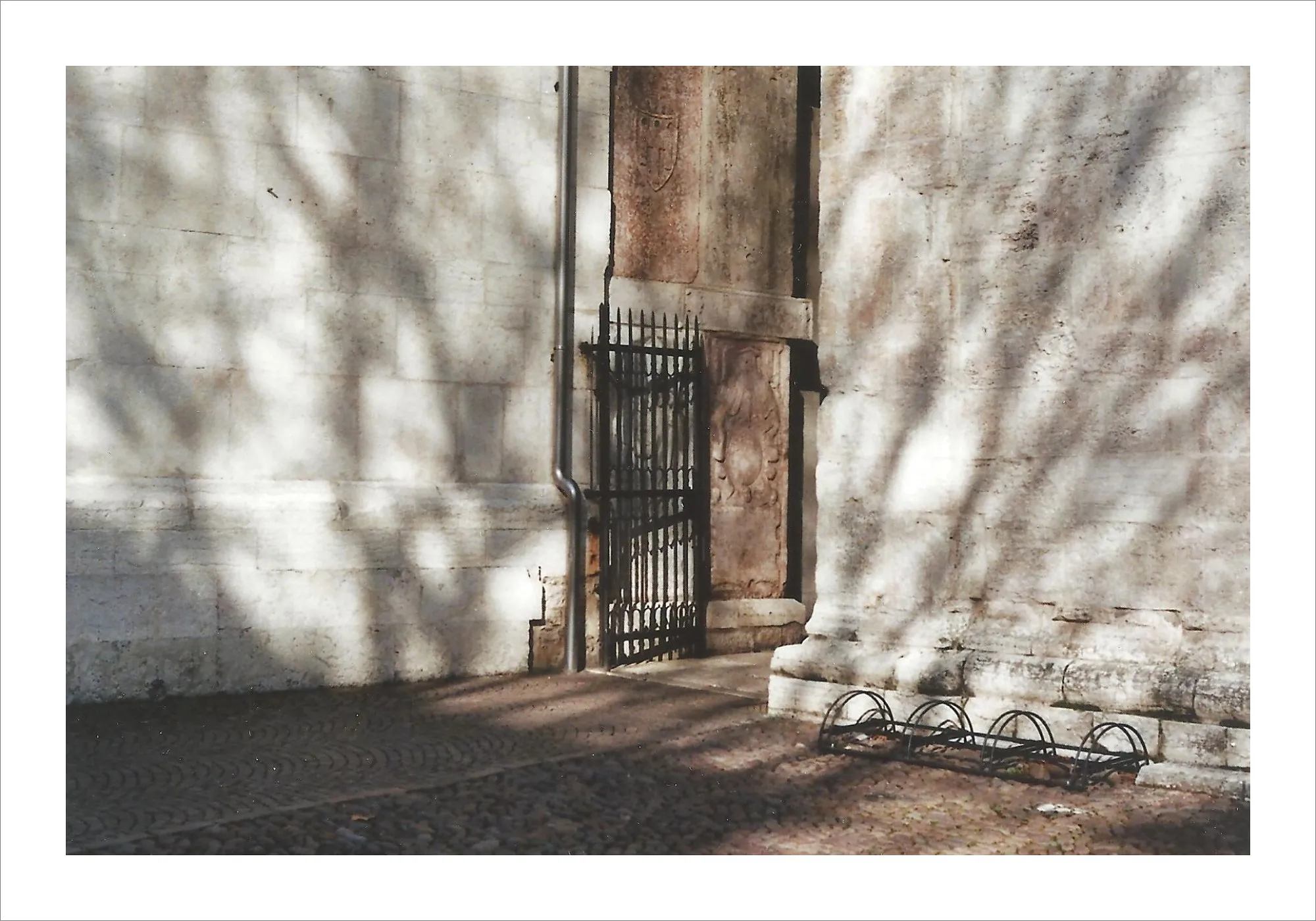 Stone doorway with iron gate and dappled shadows on wall.