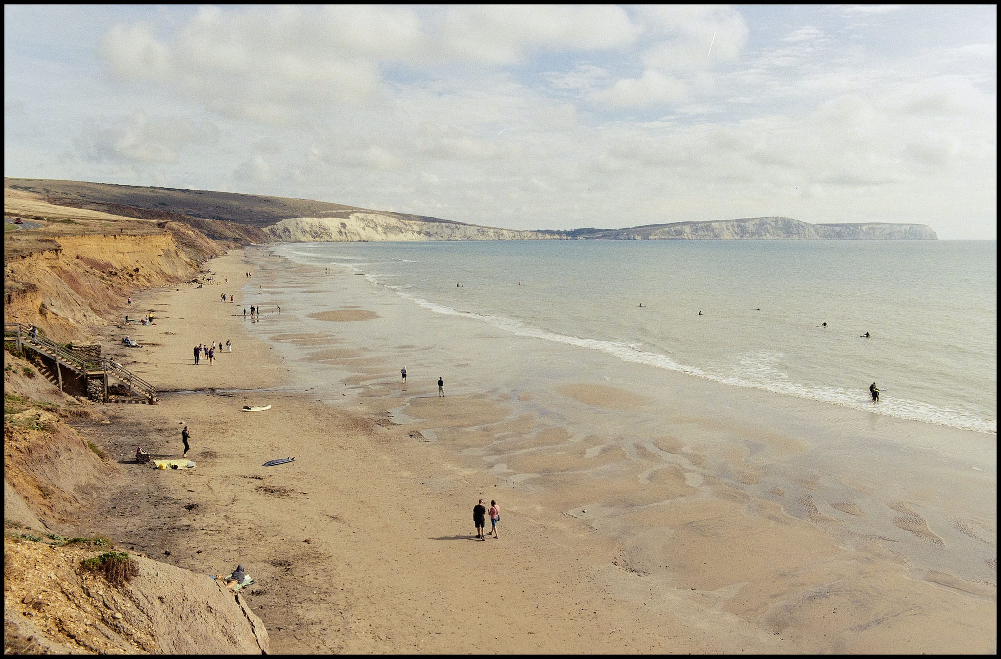 Wide beach view with cliffs and people at low tide in England.