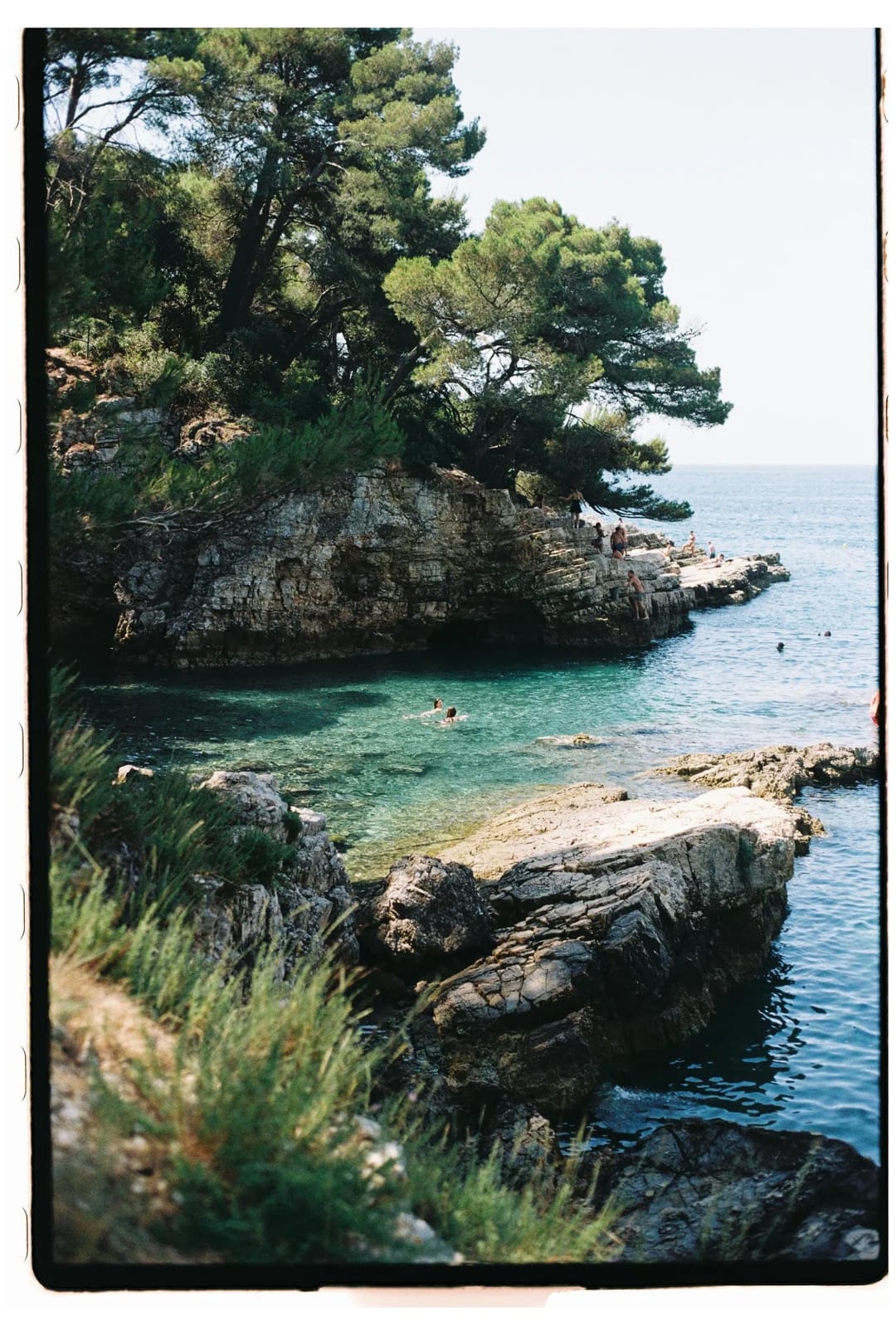 Scenic seaside cliff with people enjoying the clear water below.