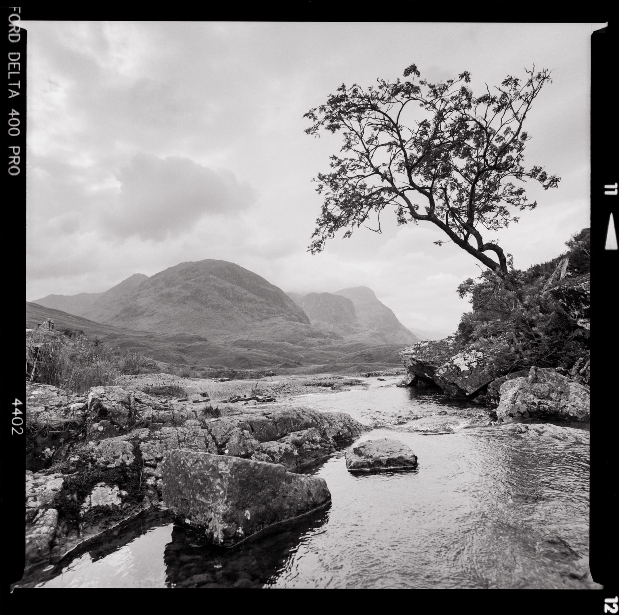 A riverbed with large rocks and misty mountains in the distance.