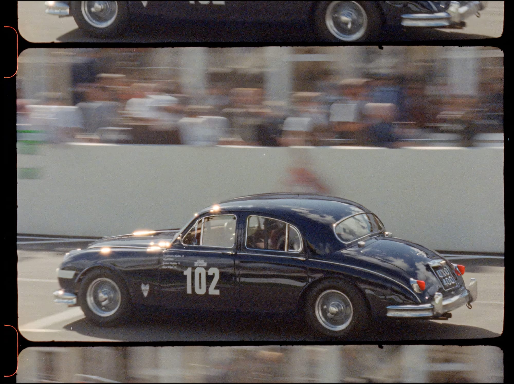 Black racing sedan with motion-blurred crowd.