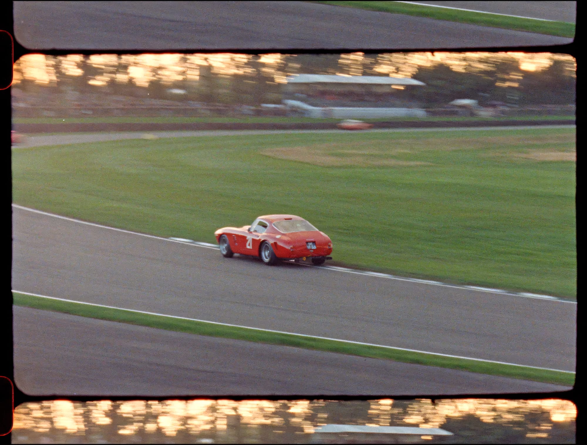 Red racing coupe on track with background blur.