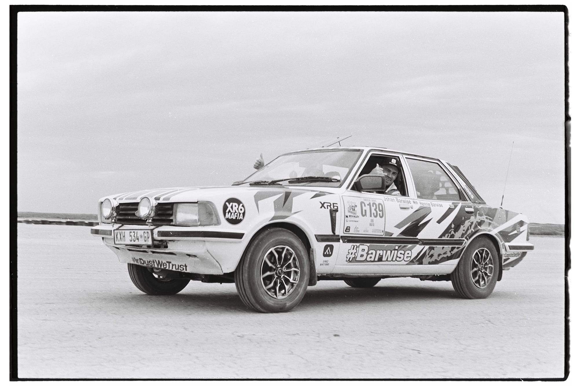 White racing sedan with sponsor decals on salt pan.