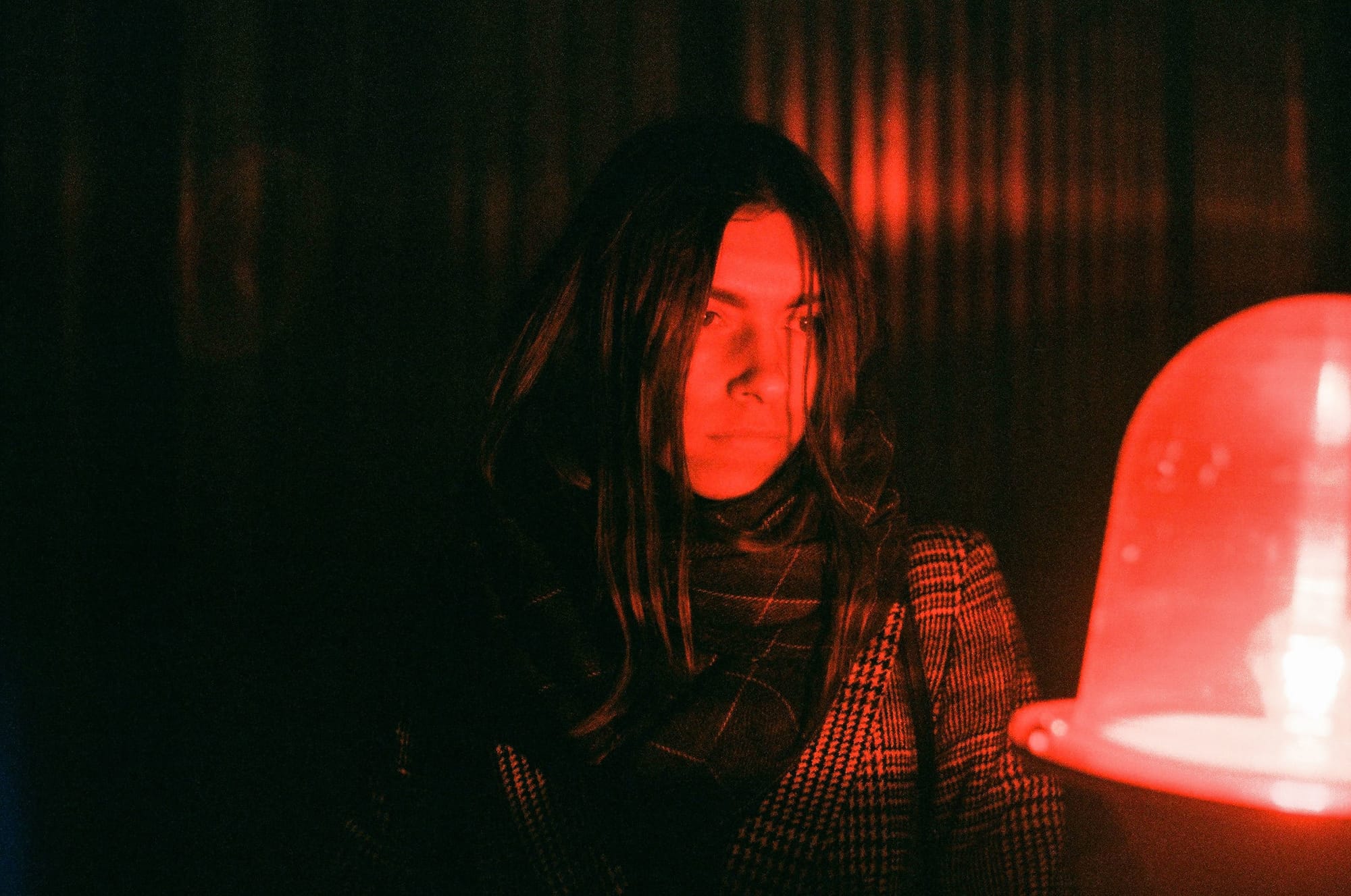 Woman standing in front of red neon light in an industrial setting.