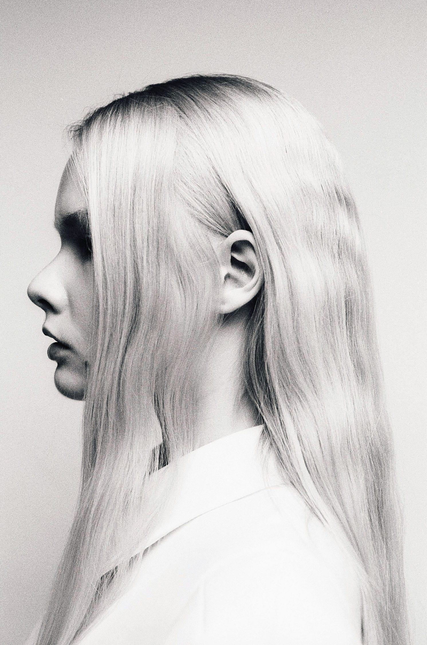 Profile view of woman with long blonde hair against plain background.