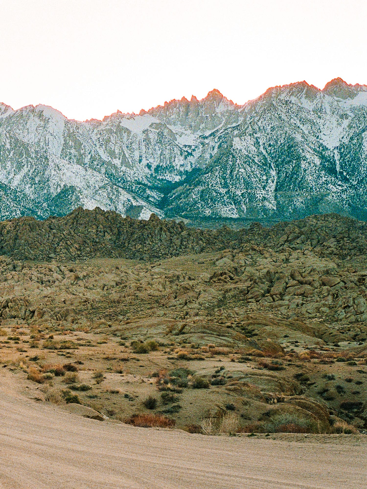 Mountain range shows color-shifted peaks above desert scrubland.