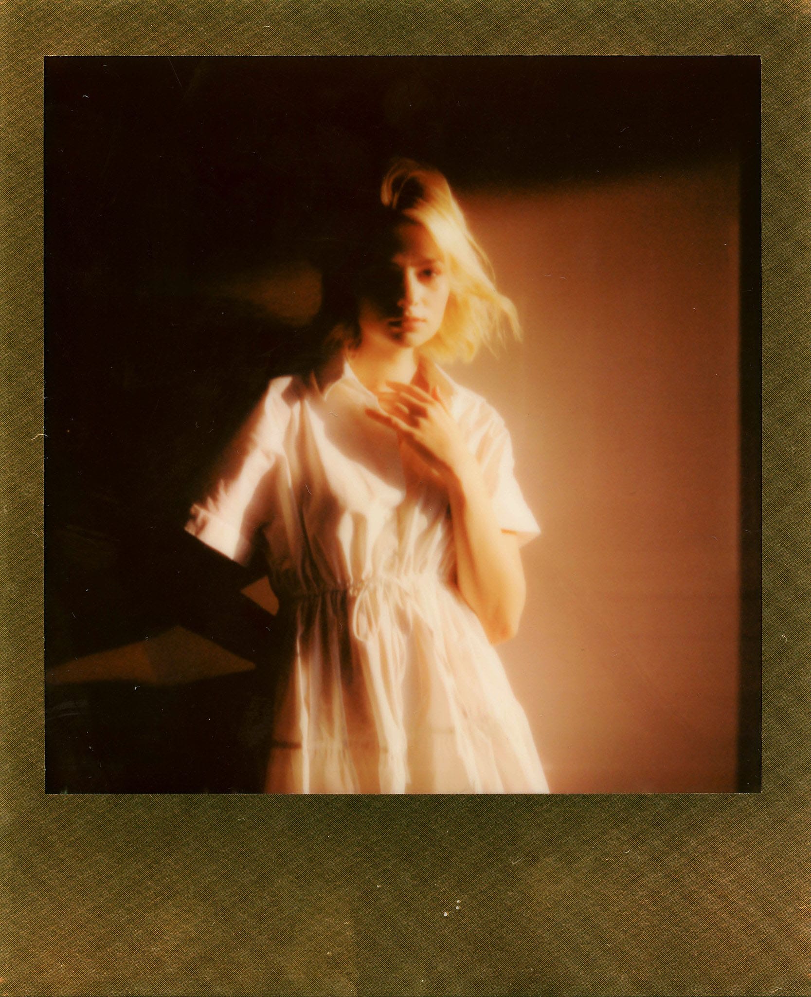 Polaroid portrait of a blonde in white dress with warm orange tones.
