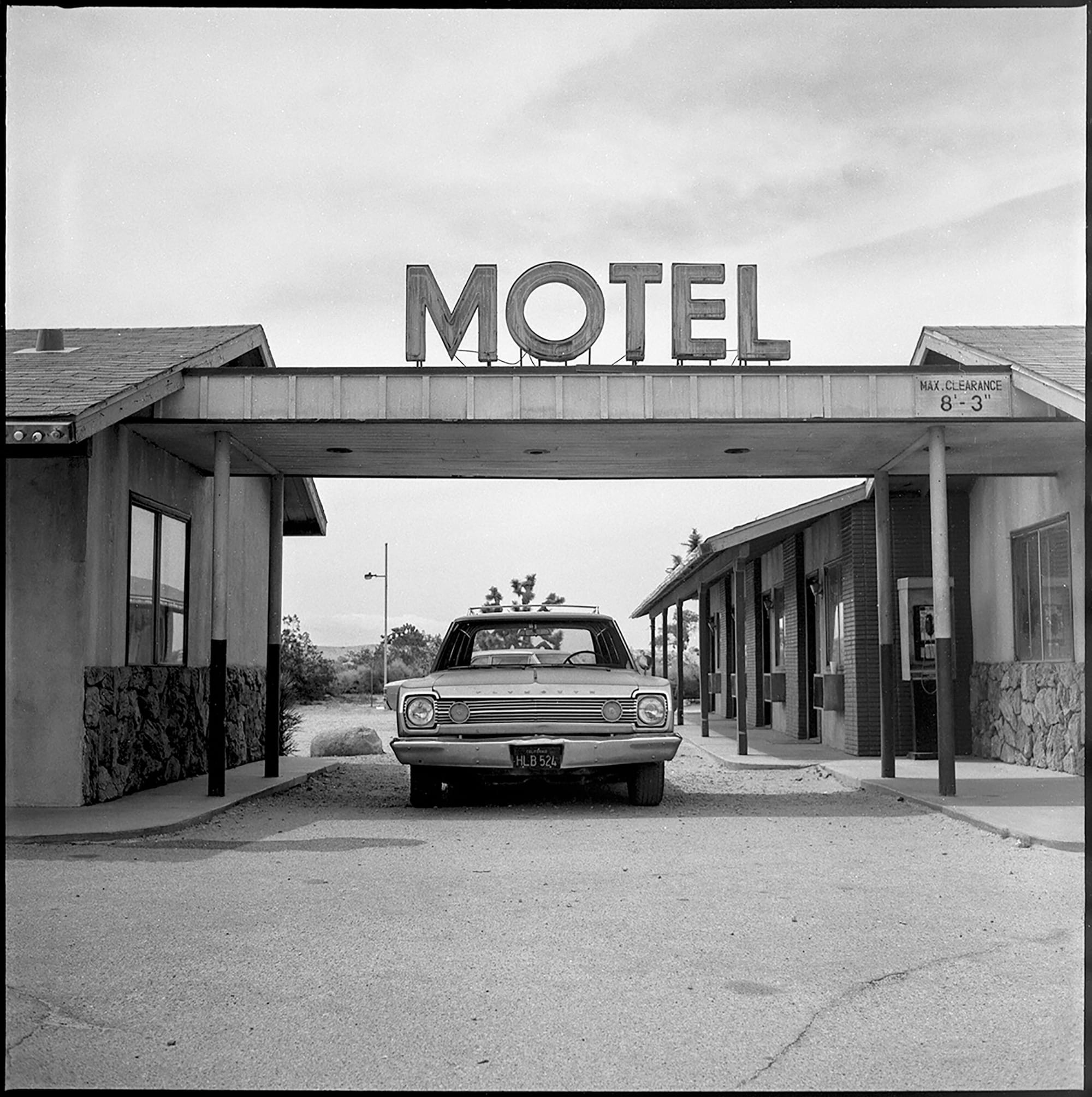 Vintage car parked under motel sign in the Californian desert.