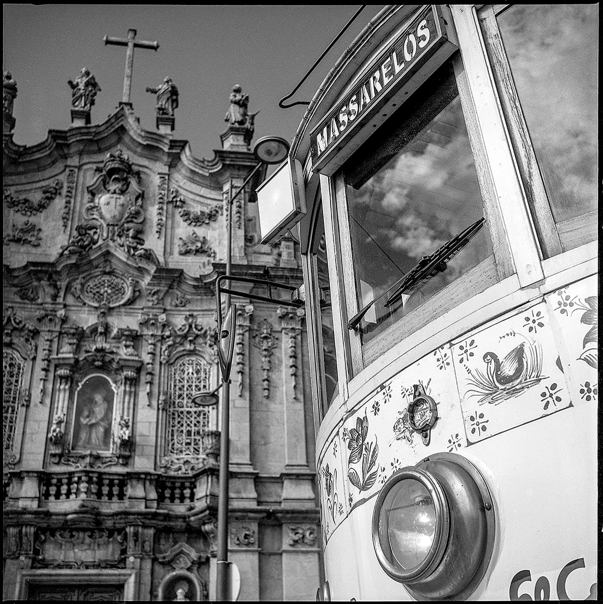 Decorated tram front reflects ornate church facade in Porto.