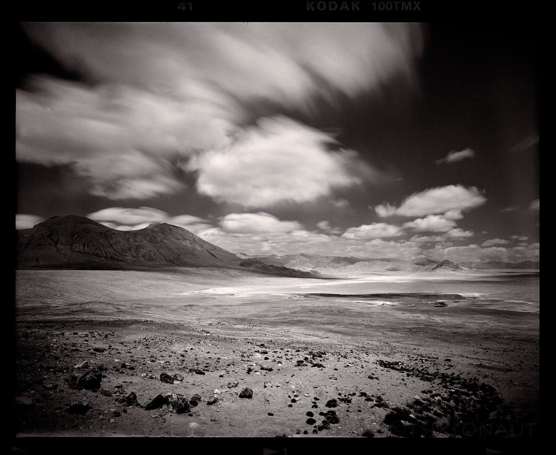 Long exposure blurs clouds over remote coastal landscape.