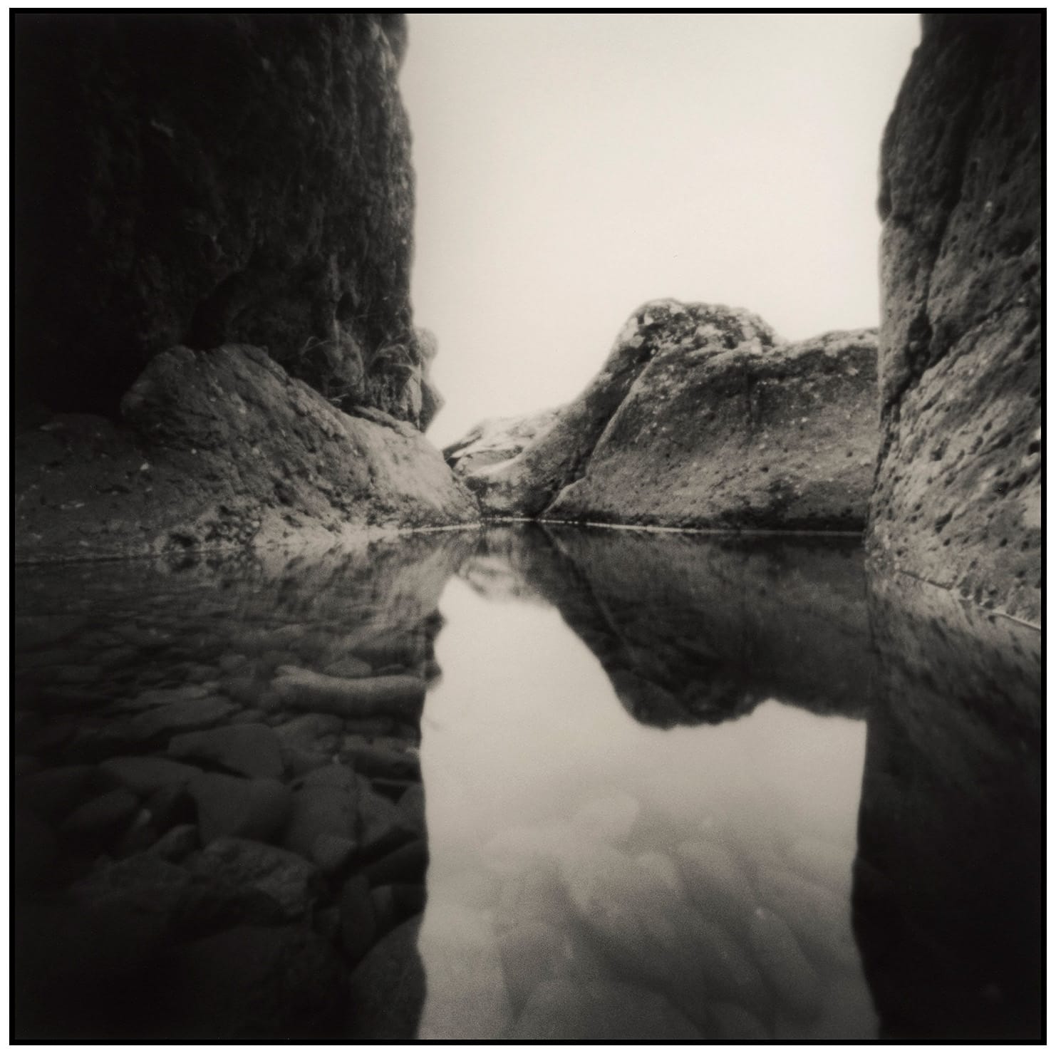Canyon walls reflected in still water creating symmetrical composition between rock formations.