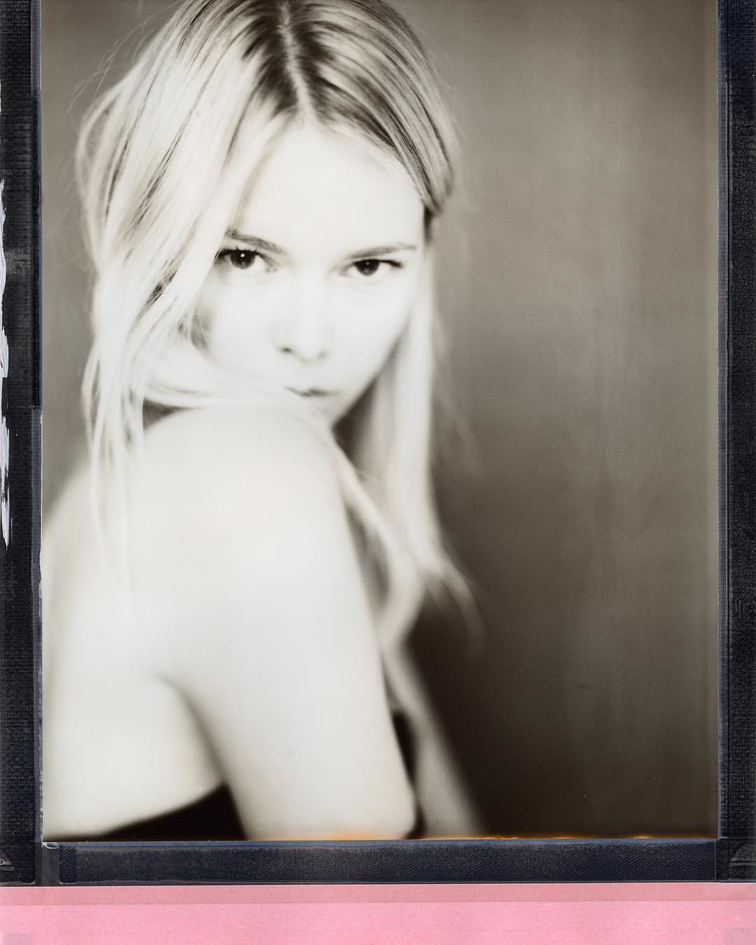 Soft focus portrait of blonde woman on instant film with pink chemical strip border.