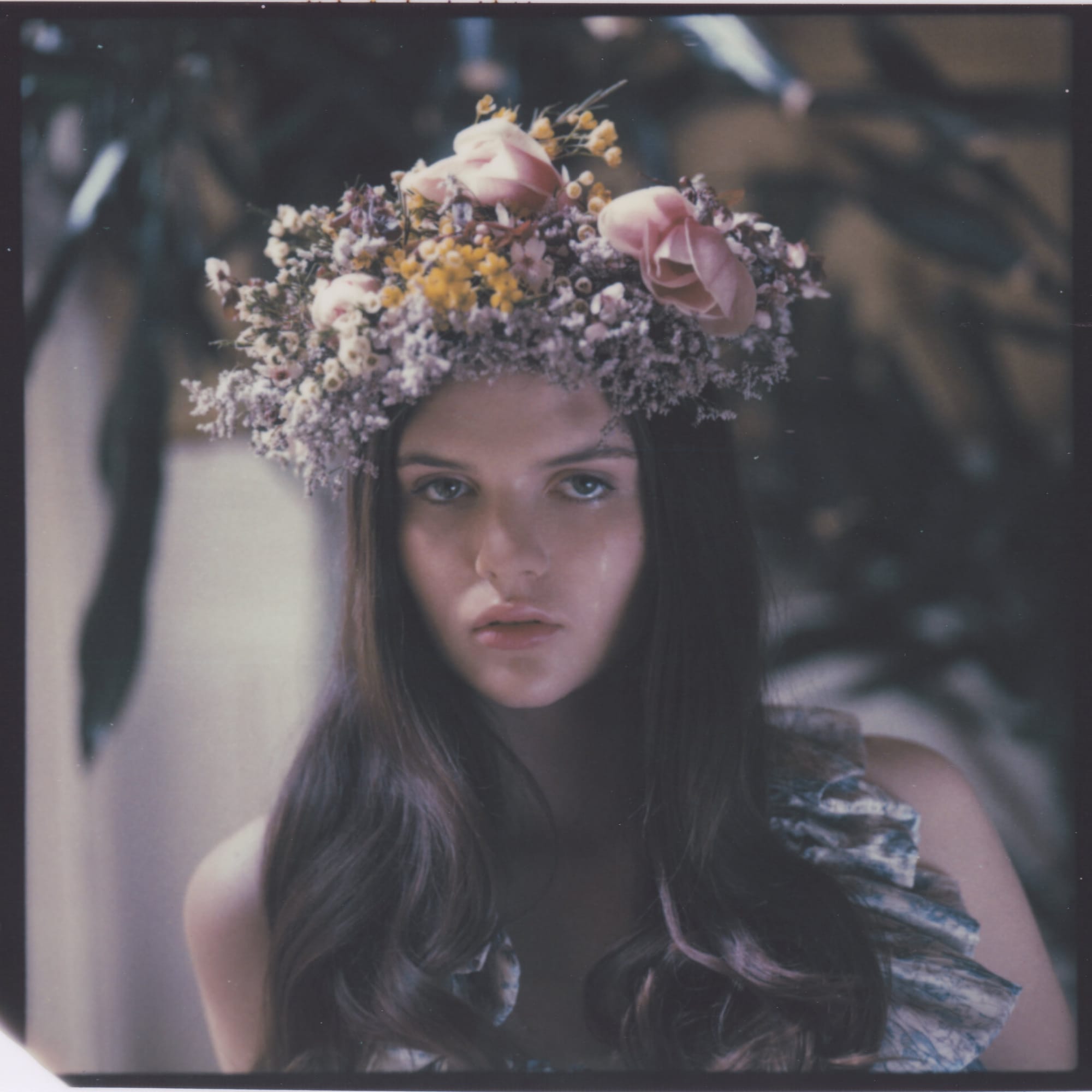 Close portrait of model wearing elaborate crown of dried flowers and roses soft focus.