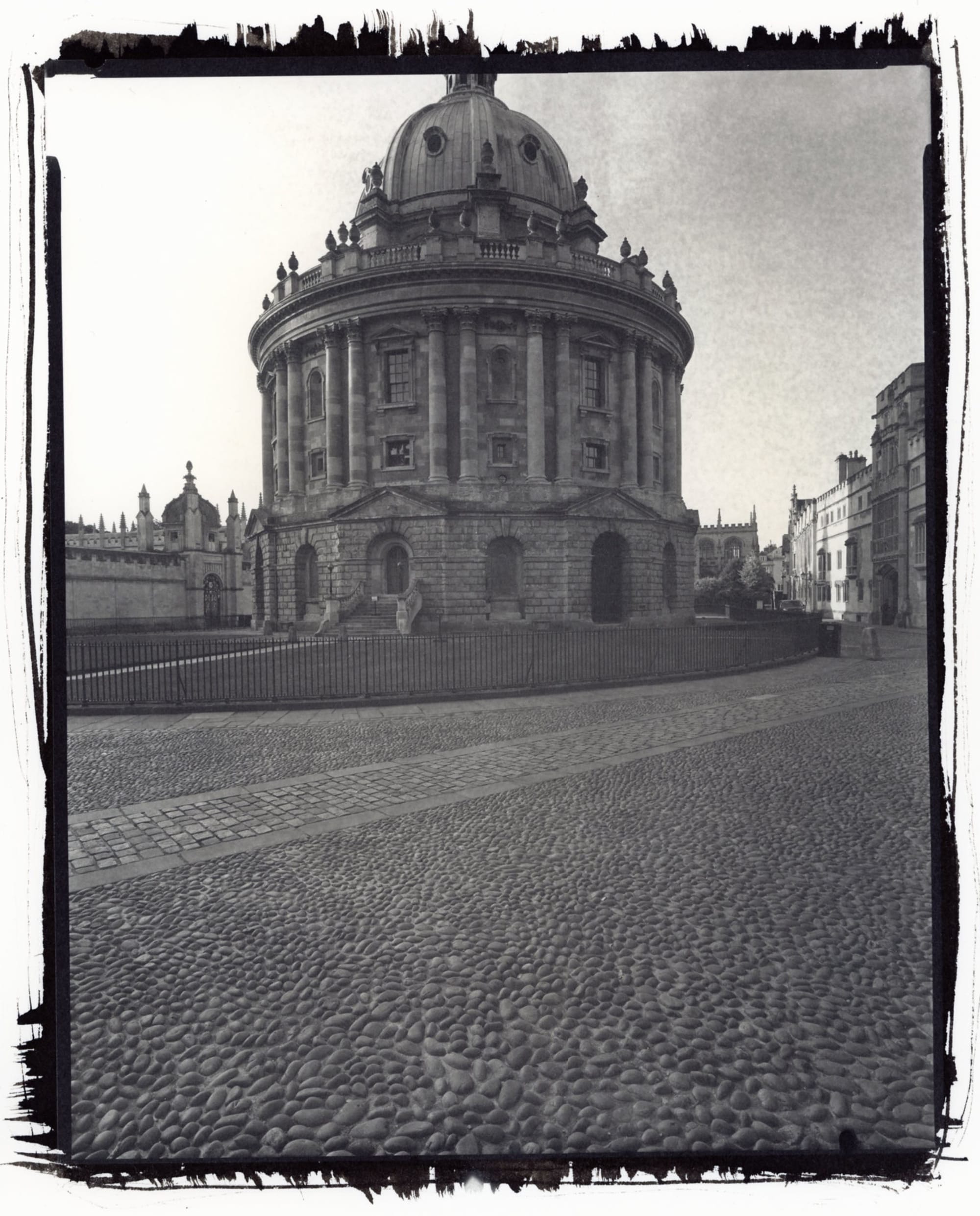 Radcliffe Camera Oxford with domed architecture on empty cobblestone plaza black white.